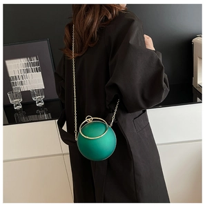 Macro view of matte green spherical bag with gold metal handle and chain strap detail