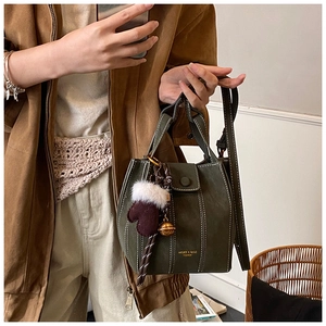 Detail of dark green bucket bag with contrast stitching and festive glove charm pendant