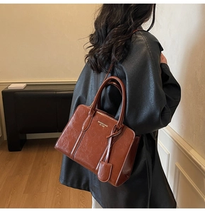 Detail of vintage brown leather tote bag with gold branding and small card holder charm