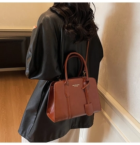 Close-up of brown leather handbag texture with gold lettering and stylish side pendant