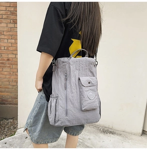 Detail of grey wrinkled nylon backpack with snap pocket and side drawstring pocket