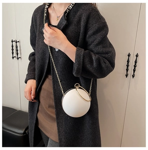 Detail of a spherical acrylic evening bag with a gold ring handle and chain strap