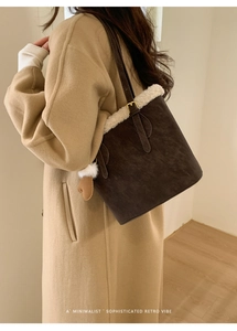 Detail of dark brown suede shoulder bag with plush white faux fur trim and heart charm