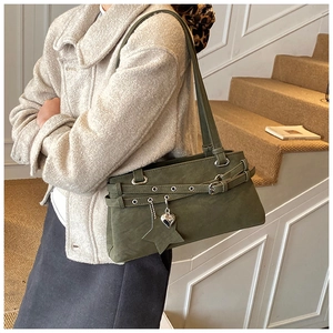 Detail of dark green matte shoulder bag with metallic eyelets and decorative charms
