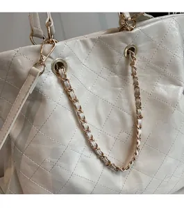 Detail of off-white quilted tote bag showing leather texture and gold chain strap