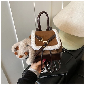 Detail of brown leather mini backpack with white faux fur trim and cute elephant charm