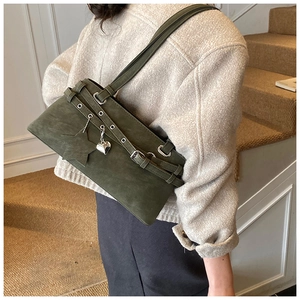 Detail of dark olive green suede Boston bag with star and heart charms on a shoulder strap