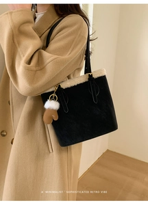 Detail of retro black suede tote bag with white plush trim and glove bag charm