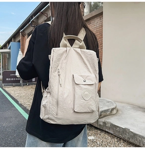 Outdoor back view of a woman wearing the cream white textured nylon backpack on the street