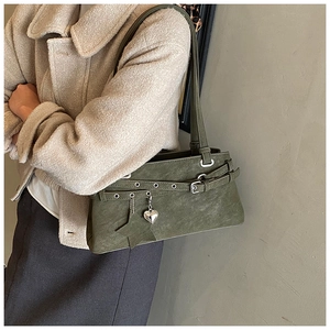 Detail of green shoulder bag featuring silver buckles and heart-shaped metal pendants
