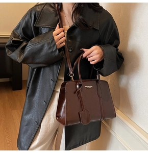 Detail shot of vintage coffee brown crossbody bag with gold text on premium faux leather