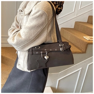 Detail of dark brown shoulder bag with silver eyelets and star heart charms on a model