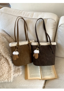 Détail de sacs seaux en daim avec bordure en fausse fourrure et charms gants