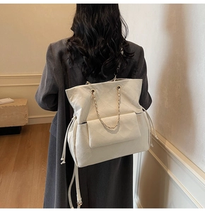 Detailed view of white quilted backpack with gold chain handles and drawstring closure