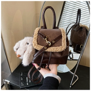 Detailed view of a brown vintage backpack with fur trim and a plush bunny keychain