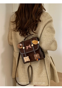 Detail of retro brown satchel with cute cookie patches shown on model back