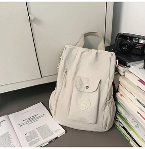 Detailed view of beige casual backpack featuring natural pleated fabric and snap pocket