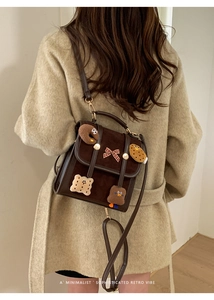 Detail of vintage brown suede backpack with 3D cartoon patches and a red plaid bow