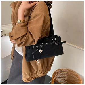 Detail of black crossbody bag featuring metal star heart charms and eyelet buckle strap