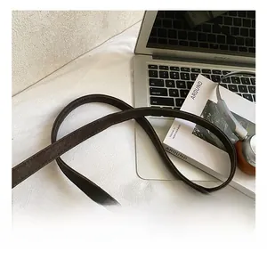 Détail de la bandoulière réglable en cuir marron foncé avec coutures soignées sur un sac