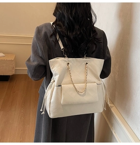 Detail of cream quilted tote bag with gold chain handles and drawstring closure
