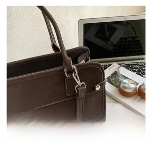 Gros plan détaillé du crochet métallique et des coutures de la bandoulière du sac marron