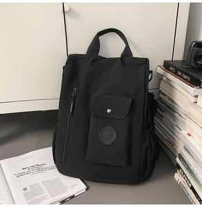 Close-up of black nylon backpack featuring side zipper and buckle pocket details