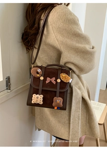 Macro shot of dark brown suede flap bag with cookie plush patches and adjustable strap