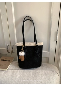 Close-up of black suede tote bag with white shearling trim and cute glove pendant