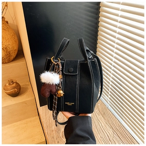 Detail of black matte bucket bag with white stitching and festive winter charms