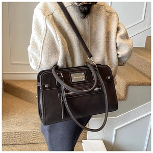 Detail of dark brown matte shoulder bag featuring silver logo and versatile straps