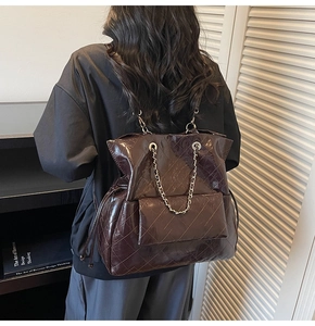 Close-up of quilted dark red leather tote featuring glossy patent finish and chain strap
