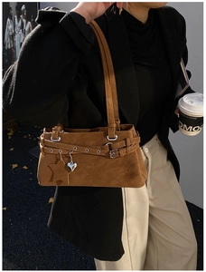 Close-up of a vintage brown suede Boston bag with metallic heart and star charms