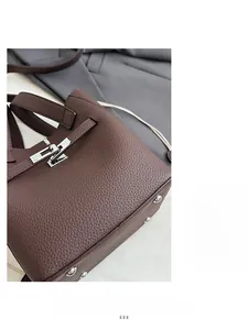 Detail of dark coffee leather bucket bag featuring silver lock and pebble grain texture