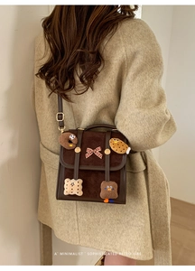 Close-up of retro brown crossbody bag with cartoon cookies and a plaid bow on a model