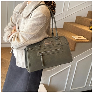 Close-up of matte grey-green tote bag with metal nameplate and front zipper detail