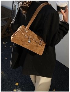 Detail view of brown suede shoulder bag featuring a star patch and heart metal charm