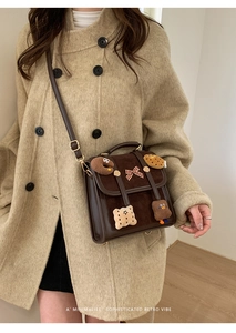 Detail view of brown retro shoulder bag with plush bear charms and double buckles