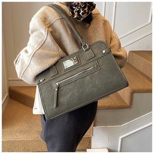 Close-up of textured faux leather shoulder bag with decorative metal plate and zipper