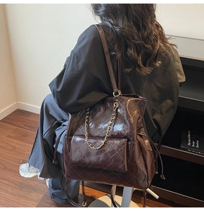 Detail of dark brown glossy leather tote featuring quilted pattern and chain strap