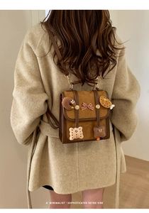Detail of retro brown backpack with plush cookies and bow charms on model back