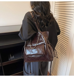 Detail view of large dark brown quilted tote bag with oily leather finish and chain trim