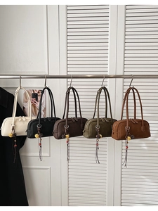 Five assorted retro leather shoulder bags with tassel charms hanging on a metal rack