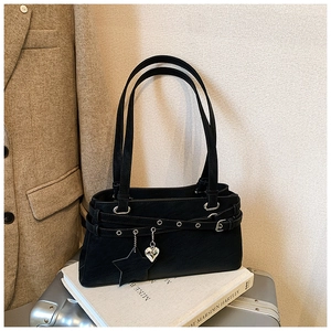 Detail of black leather Boston bag with star charm and silver heart pendant on a book