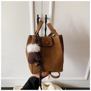 Detailed shot of brown suede bucket bag with gold lettering and plush glove charm