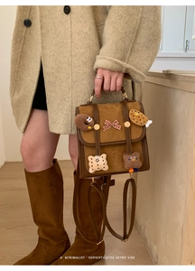 Close-up of retro brown backpack with cute plush cookie charms and a plaid ribbon bow