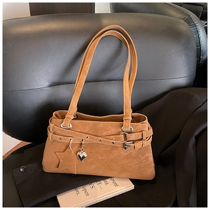 Detail of brown faux leather Boston bag with star charm and metallic heart pendant