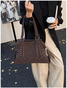 Détail du sac cabas en daim marron avec rivets argentés et pompon à franges long