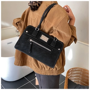 Rear view of a model wearing a black matte shoulder bag with metallic zipper detail