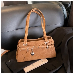 Detail of tan suede Boston bag featuring a heart metal charm and star leather tag